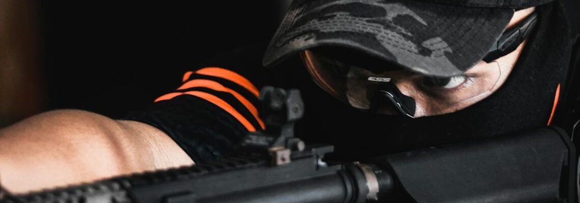 A soldier in camouflage uniform aiming a gun in a tactical setting, showcasing focus and precision.