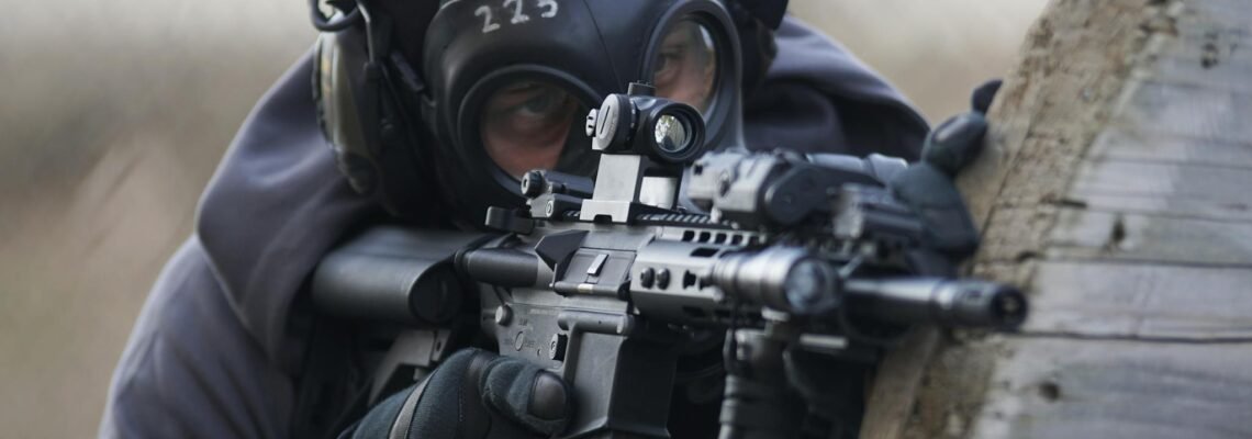 A tactical soldier in full gear aiming a rifle during an operation outdoors.
