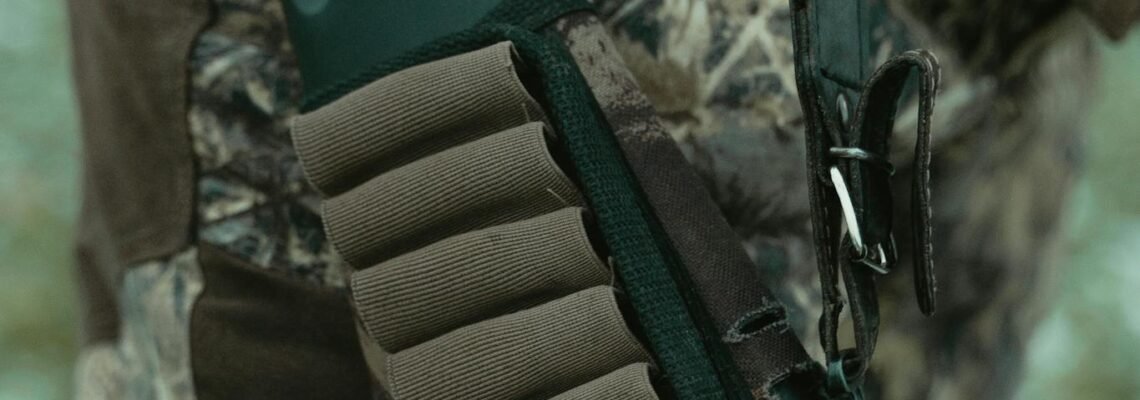 Close-up of a rifle with ammunition holder and camouflage clothing, perfect for hunting themes.