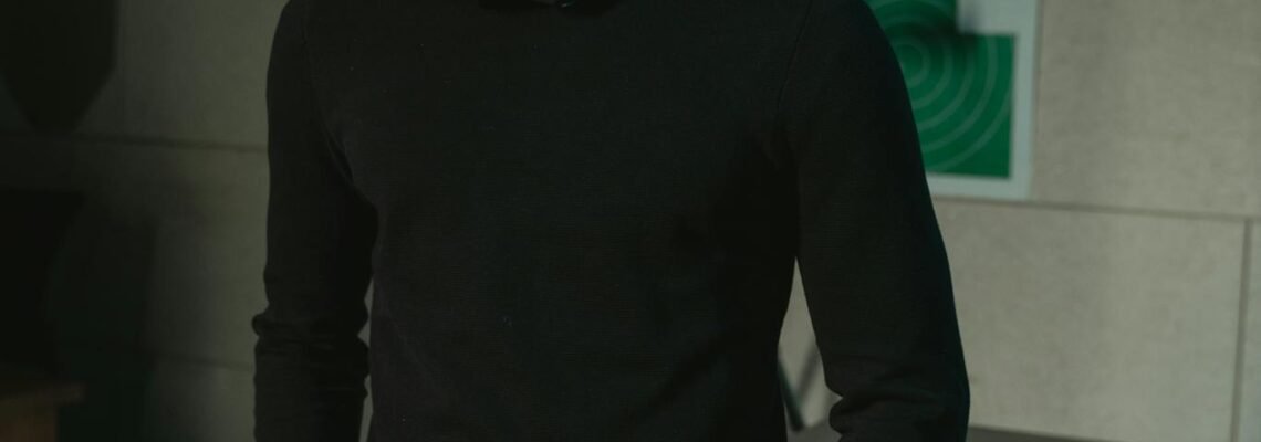 Man wearing safety glasses standing in shooting range with rifle and cartridges in view.