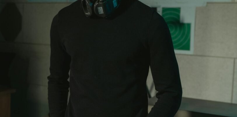 Man wearing safety glasses standing in shooting range with rifle and cartridges in view.